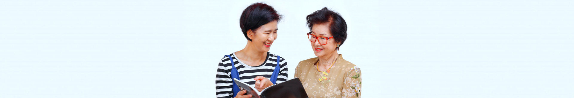 caregiver and a senior woman reading a book